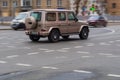 Back view of beige Mercedes G-class car riding on the road on high speed. Shiny SUV car in motion. Urban scene with riding vehicle