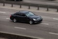 Mercedes black rides on the road. Against a background of blurred trees