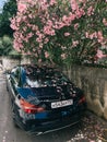 Mercedes CLA 200 parked near a stone fence under a blooming pink oleander bush