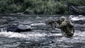 Mercenary military sniper during a sabotage mission behind enemy lines. He stands waist-deep in the river and aims at Royalty Free Stock Photo