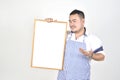 Merchant Asian man in white and blue apron to holding blank white broad for put some text or wording for present advertising Royalty Free Stock Photo