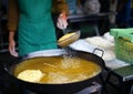 Merchant fries crispy yellow noodles on frying grate in hot oil big pan. Royalty Free Stock Photo