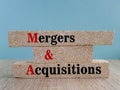 Mergers and acquisitions symbol. Concept word mergers and acquisitions on brick blocks. Beautiful blue background, wooden table. Royalty Free Stock Photo