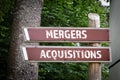 Mergers and Acquisitions. Wooden signs and directional arrows