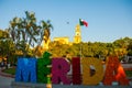 Merida, Mexico. Colorful Merida sign in Plaza Grande. San Ildefonso cathedral in the evening. Mexican flag flutters on air.