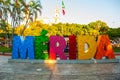 Merida, Mexico. Colorful Merida sign in Plaza Grande. San Ildefonso cathedral in the evening. Mexican flag flutters on air.