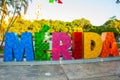 Merida, Mexico. Colorful Merida sign in Plaza Grande. San Ildefonso cathedral in the evening. Mexican flag flutters on air.