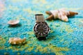 Diving watch of the famous Swiss brand Mido, which is on a background with blue sand, shells and
