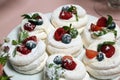 Meringue nests with strawberry cream, fresh strawberries, raspberries, blueberries and a mint leaf. Closeup Royalty Free Stock Photo