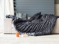 Merino wool grey blanket lying on white sofa with an orange cup Royalty Free Stock Photo