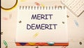 Merit, demerit and its retributions at the level of the individual. MERIT DEMERIT words in a notebook on the table