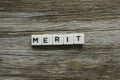 Merit word made of square letter word on wooden background