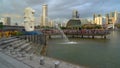 Merlion and many tourists with skyscraper buildings in Singapore Downtown and Financial district at sunset.