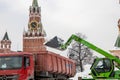 Merlo front-end loader unloads snow into a large semi-trailer against the backdrop of the Spasskaya Tower of the Moscow