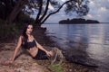 Mermaid Posing With Net Near Sea on Rocks While Wearing Artistic Makeup and Black Shiny Tail Covered With Colorful Spangles Posing