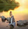 Mermaid on the stone. sitting in the sunset on the rocks. Royalty Free Stock Photo