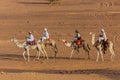 MEROE, SUDAN - MARCH 4, 2019: Locals ride camels near the pyramids of Meroe, Sud