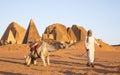 Sudanese man with his camel in a desert near Meroe Pyramids