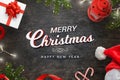 Merr Christmas text on black wooden table surrrounded with Christmas tree, gift, sweets, lights