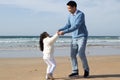 Merry Asian family walking together on beach