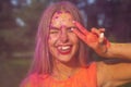 Merry blonde girl showing peace gesture celebrating Holi festival