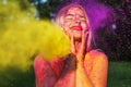 Merry blonde woman posing with exploding yellow paint at summer