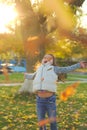 A merry child scatters an armful of yellow fallen leaves. Sunny sunset in autumn park outdoors