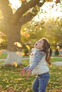 A merry child scatters an armful of yellow fallen leaves. Sunny sunset in autumn park outdoors Royalty Free Stock Photo