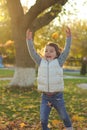 A merry child scatters an armful of yellow fallen leaves. Sunny sunset in autumn park outdoors Royalty Free Stock Photo