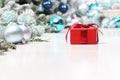 Merry christmas background, red gift present package with bow and ribbon, next to blue Christmas balls, useful as a greeting card Royalty Free Stock Photo