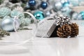 Merry christmas background, silver gift present box with bow and ribbon, next to blue Christmas balls and pine cones, useful as a Royalty Free Stock Photo