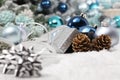 Merry christmas background, silver gift present box with bow and ribbon, next to blue Christmas balls and pine cones, useful as a Royalty Free Stock Photo