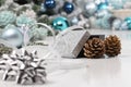 Merry christmas background, silver gift present box with bow and ribbon, next to blue Christmas balls and pine cones, useful as a Royalty Free Stock Photo