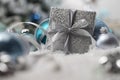 Merry christmas background, silver gift present box with bow and ribbon, next to blue Christmas balls and snowflakes, useful as a Royalty Free Stock Photo