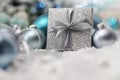 Merry christmas background, silver gift present box with bow and ribbon, next to blue Christmas balls and snowflakes, useful as a Royalty Free Stock Photo