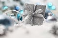 Merry christmas background, silver gift present box with bow and ribbon, next to blue Christmas balls and snowflakes, useful as a Royalty Free Stock Photo