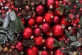 Merry christmas background, top view of stack of colorful glass balls in red with mistletoe and pine cones, useful as a greeting Royalty Free Stock Photo