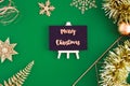 Merry christmas on blackboard top view with gold christmas and new year decoration ornament stuff on green paper background. Royalty Free Stock Photo