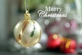 Merry Christmas. Christmas card and greeting with Christmas golden ball ornament hanging on blur colorful bokeh white background. Royalty Free Stock Photo