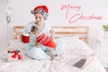 Merry Christmas card with text. Young woman in Santa hat playing with a cute puppy dog pet at home. Pet owner celebrating Royalty Free Stock Photo