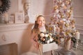 Merry Christmas celebration. Beautiful little girl in a dress lying near the Christmas tree. Winter holidays