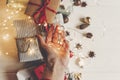 merry christmas concept flat lay. hand holding lights and presents with ornaments pine cones anise in the rustic white wooden Royalty Free Stock Photo