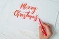 Merry Christmas congratulations. Calligrapher writes with red ink on white card. Calligraphy. Ornament font. The art of