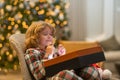 Merry Christmas. Daydreaming child crossed fingers and Christmas gift at home. Happy funny child in winter pajama near Royalty Free Stock Photo