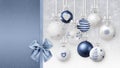 Merry Christmas decorative blue and white balls with shiny ribbons bows and glitter patterns, hanging on blurred lights snow Royalty Free Stock Photo