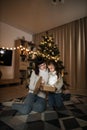 Family of two mother and little cute child girl with magic gift at home near Christmas tree. Royalty Free Stock Photo