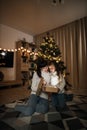 Family of two mother and little cute child girl with magic gift at home near Christmas tree. Royalty Free Stock Photo