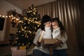 Family of two mother and little cute child girl with magic gift at home near Christmas tree. Royalty Free Stock Photo