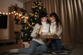 Family of two mother and little cute child girl with magic gift at home near Christmas tree. Royalty Free Stock Photo