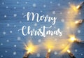 Merry Christmas festive background with garland lights on a blue wooden board.Winter holidays greeting card. Royalty Free Stock Photo